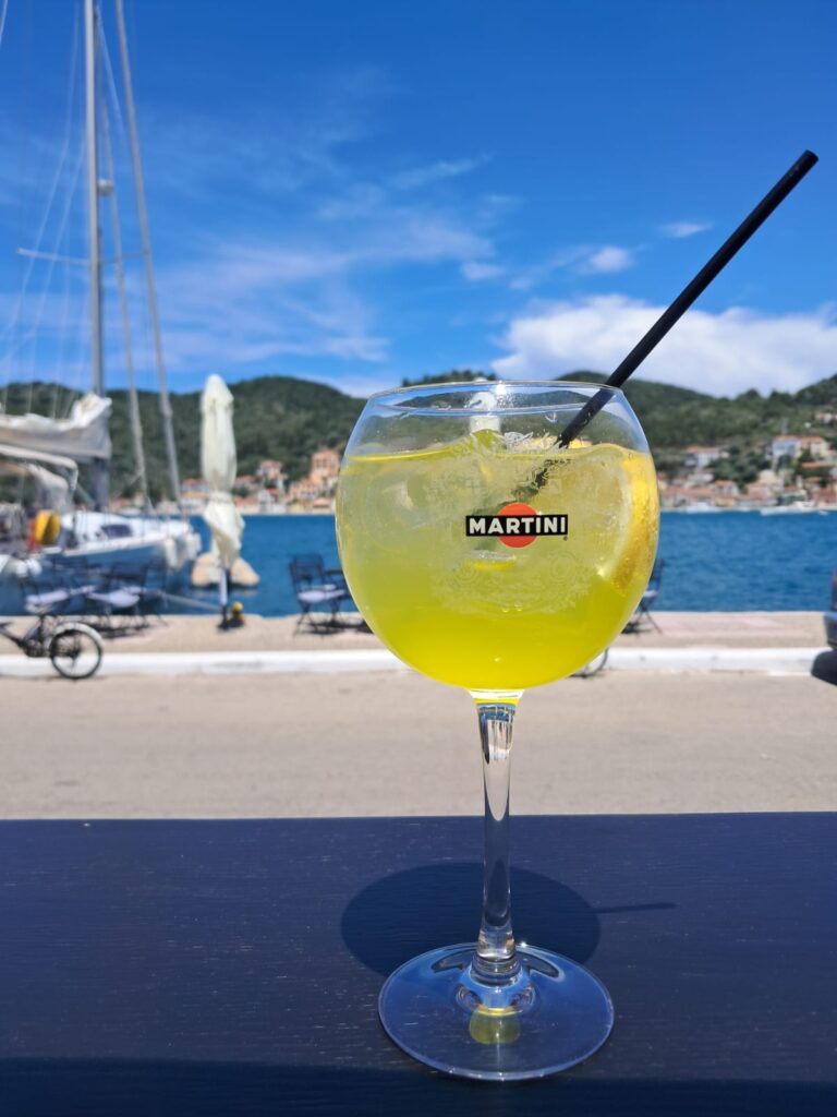 yellow cocktail in martini glass in front of pier
