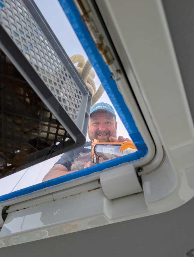 Man repairing a hatch with silicone